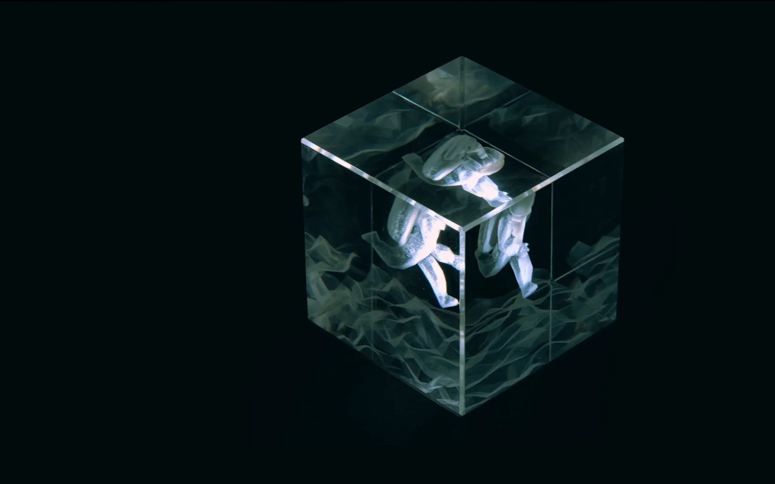 A clear crystal cube on a dark ground with a small astronaut laser engraved inside it, one frame of a stop motion run cycle.